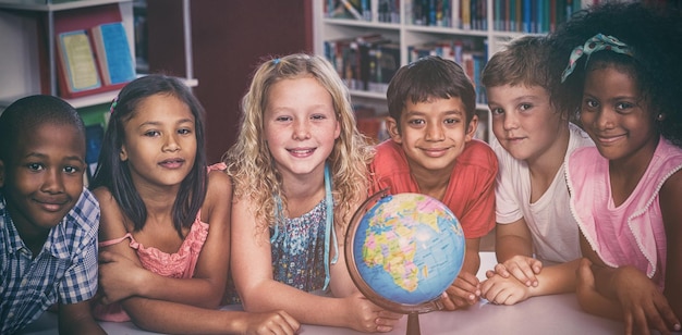 Foto lächelnde kinder mit globus auf dem tisch