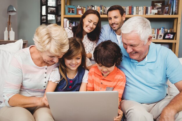 Lächelnde Kinder und Großeltern, die Laptop mit Familie verwenden