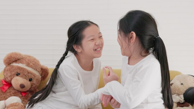 Lächelnde kleine Mädchen und ein glückliches Familienurlaubs- und Kindheitskonzept Kinder amüsieren sich zu Hause auf dem Sofa im Wohnzimmer