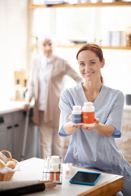 Lächelnde Krankenschwester, die zwei Packungen Vitamine hält