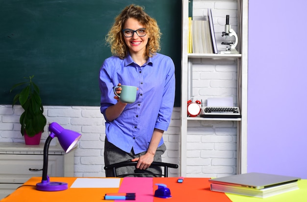 Lächelnde Lehrerin im Klassenzimmer junge Lehrerin junge Lehrerin mit Brille über grüner Tafel