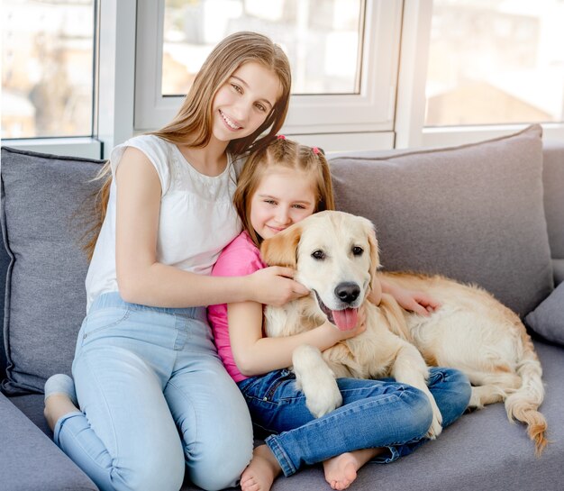 Lächelnde Mädchen, die schönen Hund im hellen Raum kuscheln