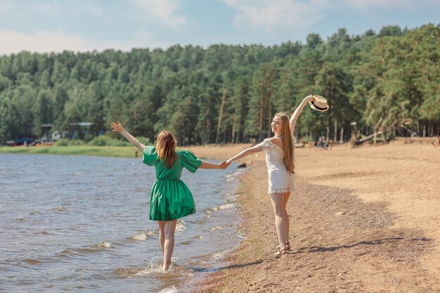 Lächelnde Mädchen gehen entlang der Küste Konzept der Freundschaft Unterhaltung und Spaß