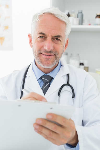 Lächelnde männliche Doktorschreibensberichte im Ärztlichen Dienst