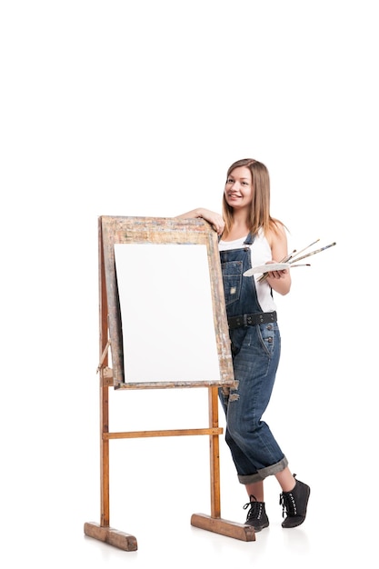 Foto lächelnde malerin mit pinsel, die am staffelei steht
