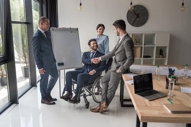 Lächelnde multikulturelle Geschäftspartner, die sich während eines Geschäftstreffens im Büro die Hand schütteln