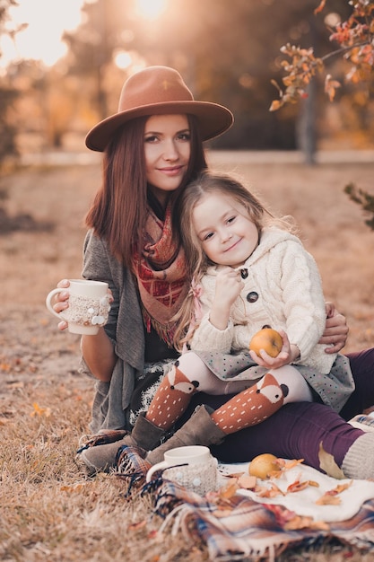 Foto lächelnde mutter, die mit ihrer kleinen kindertochter heißen tee trinkt