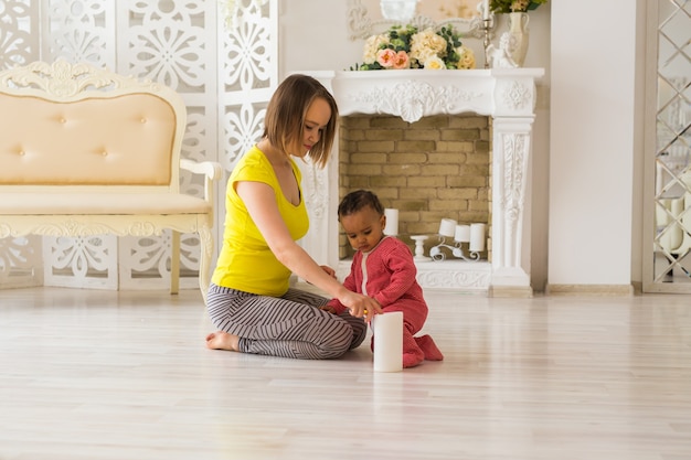 Lächelnde Mutter, die zu Hause mit Mischrasse-Baby-Sohn spielt.