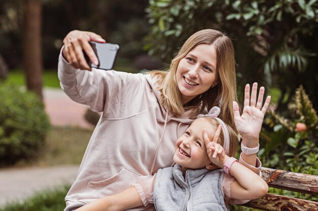 Foto lächelnde mutter macht ein selfie mit ihrer tochter im freien