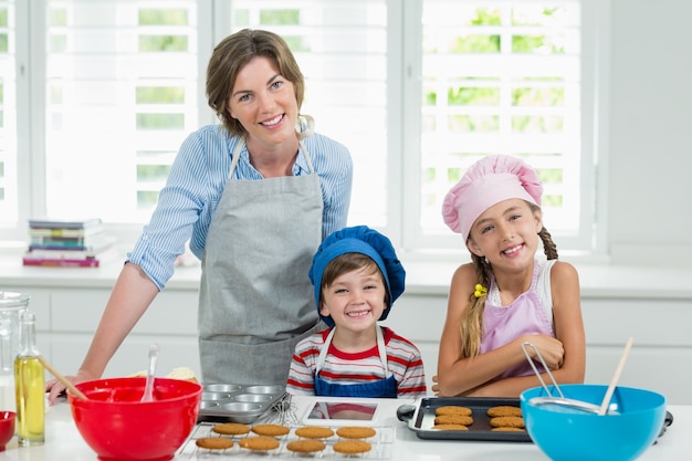 Lächelnde Mutter und Kinder, die Kekse in der Küche vorbereiten