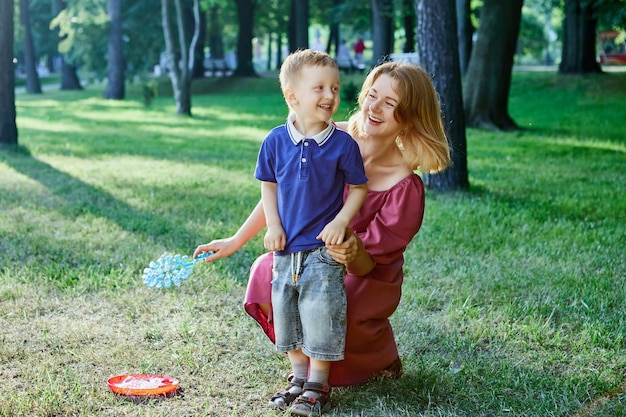 Lächelnde Mutter und kleiner Sohn gehen zusammen im Freien spazieren