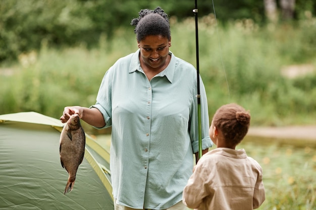 Lächelnde Mutter und Tochter beim gemeinsamen Angeln beim Camping