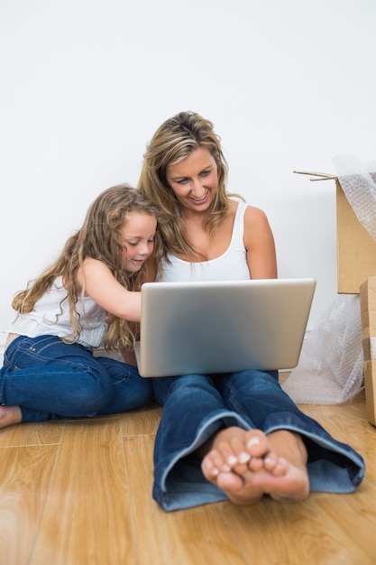 Lächelnde Mutter und Tochter, die auf dem Boden sitzt