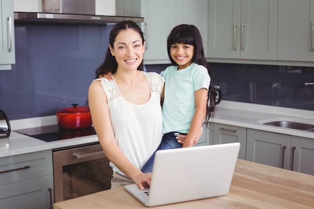 Lächelnde Mutter und Tochter, die einen Laptop verwendet