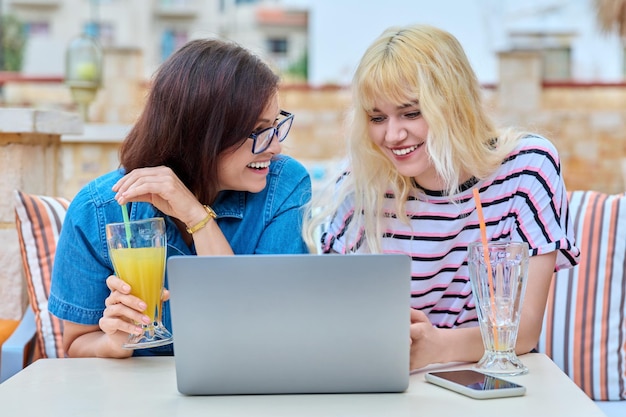 Lächelnde Mutter und Tochter im Teenageralter, die zusammen in den Laptop-Bildschirm schauen