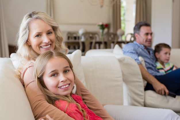 Lächelnde Mutter und Tochter sitzen zusammen im Wohnzimmer