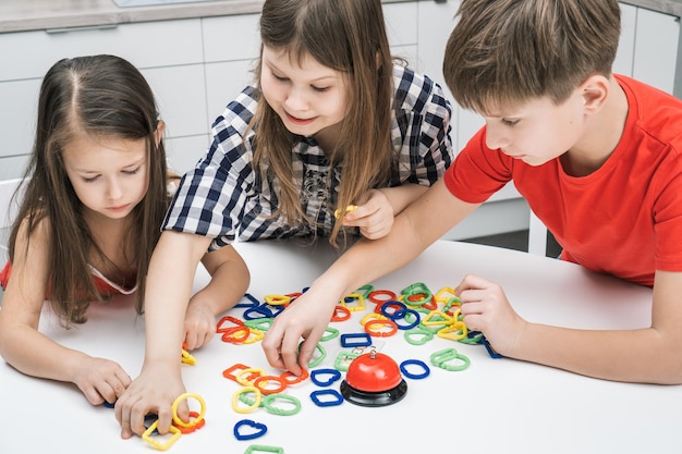 Lächelnde nachdenkliche Kinder von Jungen und Mädchen verbinden bunte Kettenfiguren zum Puzzle-Konstruktor Entwicklung von Kindern