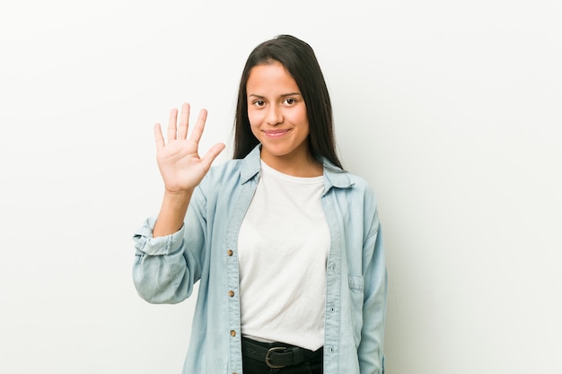 Lächelnde nette darstellende Nr. Fünf der jungen hispanischen Frau mit den Fingern.