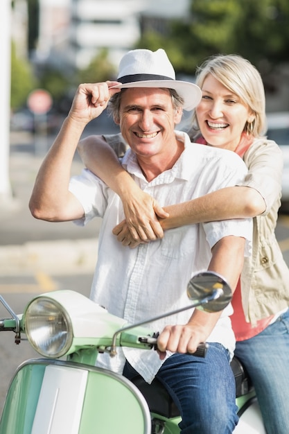 Lächelnde Paare, die Motorroller sitzen