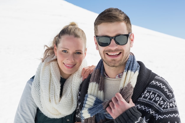 Lächelnde Paare in der warmen Kleidung auf Schnee bedeckten Landschaft
