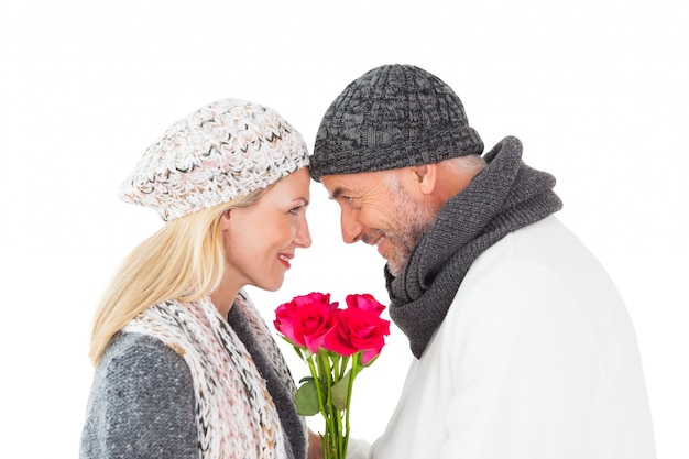 Lächelnde Paare in der Wintermode, die mit Rosen aufwirft