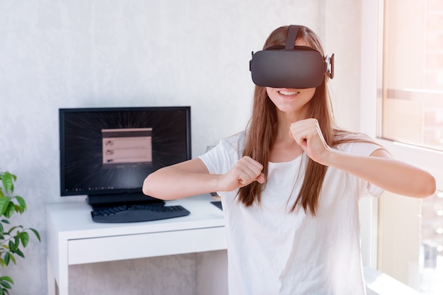 Lächelnde positive Frau, die Virtual-Reality-Brillen-Headset trägt, VR-Box. Verbindung, Technologie, neue Generation, Fortschrittskonzept. Mädchen, das versucht, Objekte in der virtuellen Realität zu berühren