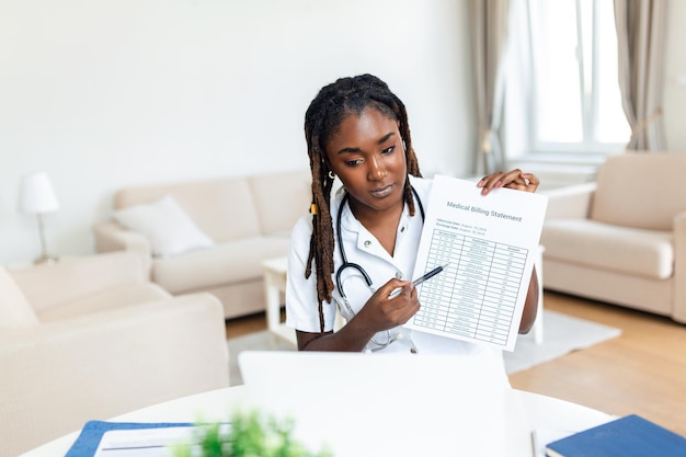 Lächelnde professionelle Ärztin in Uniform, die sich Notizen in einem medizinischen Journal macht, das die Krankheitsgeschichte des Patienten füllt und auf den Laptop-Bildschirm schaut, Student, der sich ein Webinar ansieht