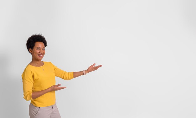 Lächelnde Promoterin präsentiert neues Produkt auf Kopierfläche, während sie vor weißem Hintergrund steht