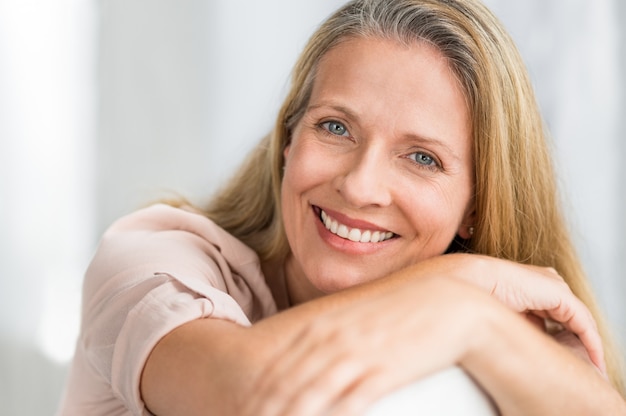 Lächelnde reife Frau auf der Couch