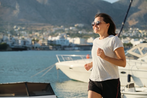 Lächelnde reife Frau beim Joggen an der Strandpromenade