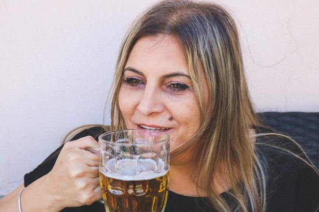 Foto lächelnde reife frau trinkt bier