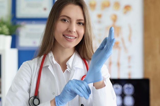 Lächelnde Ärztin, die medizinische Handschuhe anzieht