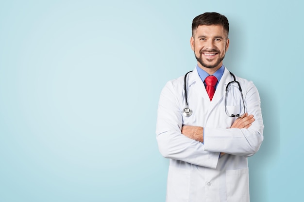 Lächelnde Ärztin im Laborkittel mit verschränkten Armen vor blauem Hintergrund
