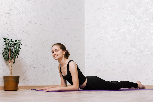 lächelnde schlanke Frau, die Yoga in Sphinx-Pose oder Cobra-Pose macht