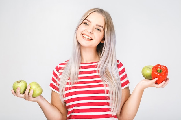 Lächelnde schöne blonde Frau, die vegane Lebensmittelzutaten hält. Isoliertes Porträt auf Weiß.