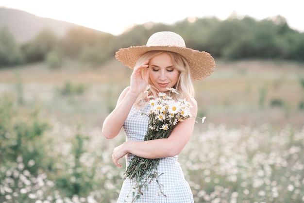 Lächelnde schöne blonde Frau mit Strauß frischer Gänseblümchen