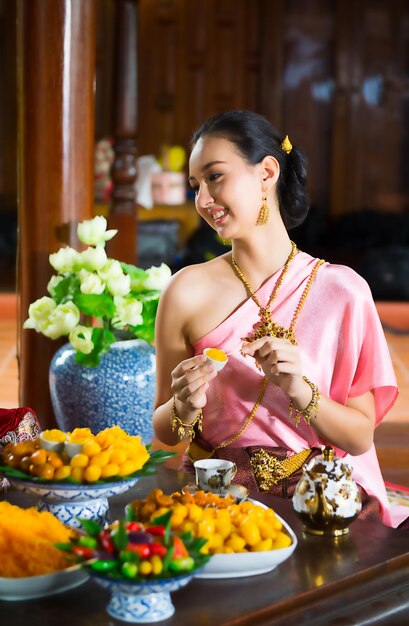 Foto lächelnde schöne frau in traditioneller kleidung und schmuck beim frühstück zu hause