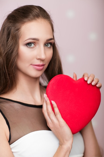 Foto lächelnde schöne lockige frau mit herzförmigen luftballons für valentinstag