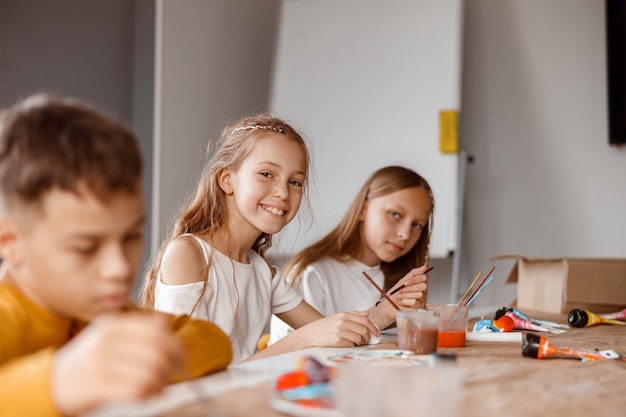 Lächelnde Schüler, die mit bunten Farben auf Papier malen