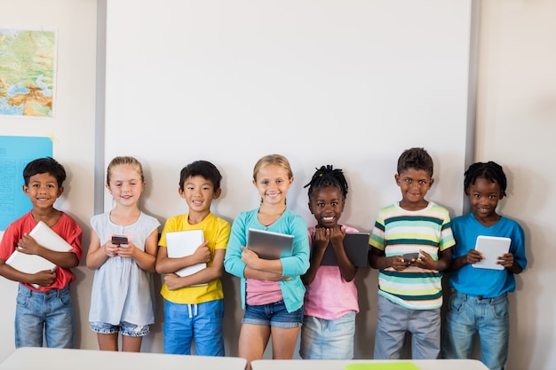 Lächelnde Schüler, die mit Technologie stehen