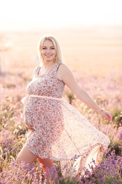 Lächelnde schwangere Frau in Lavendelblumenwiese