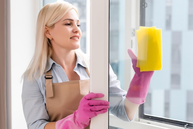 Lächelnde schwarze Frau, die Fenster mit Glasreiniger putzt