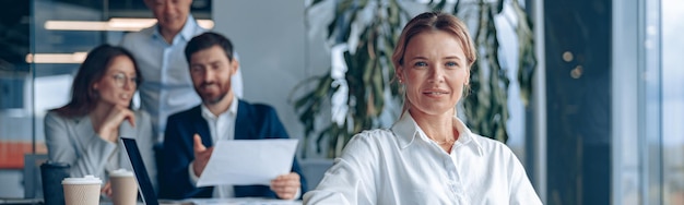 Foto lächelnde, selbstbewusste chefin, die sich im büro mit ihren kollegen im hintergrund trifft