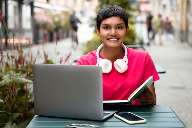 Lächelnde selbstbewusste indische Freiberuflerin mit Laptop-Computer, die online arbeitet und in die Kamera blickt