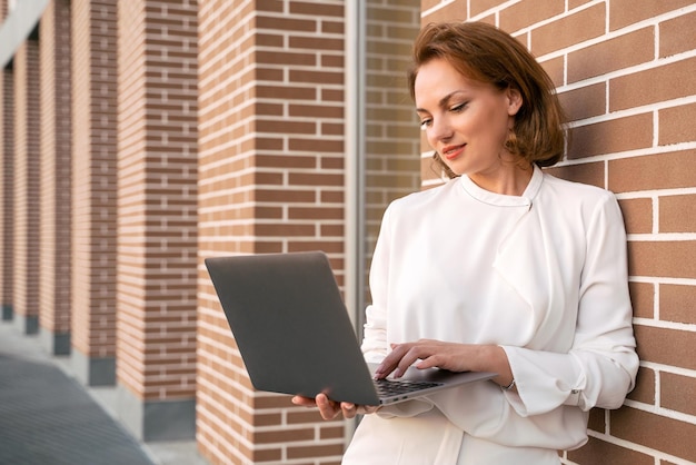 Lächelnde, stilvolle Geschäftsfrau, die online über Laptop kommuniziert und Schulungen anschaut