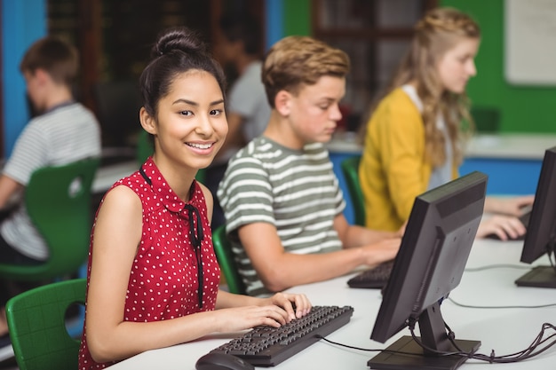 Lächelnde Studenten, die im Computerklassenzimmer studieren