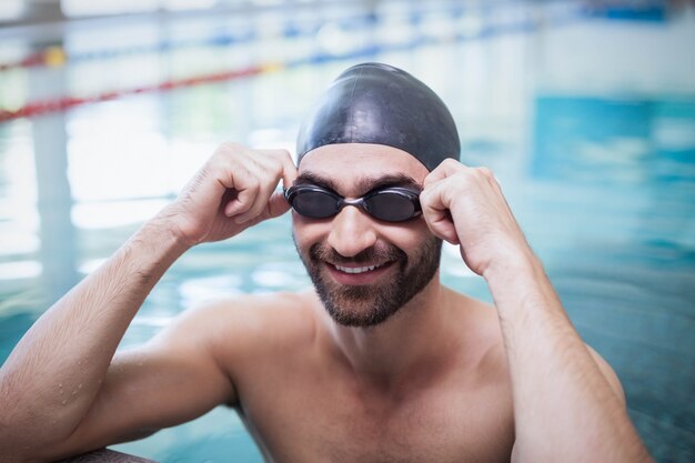 Lächelnde tragende Badekappe und Schutzbrillen des Mannes am Pool