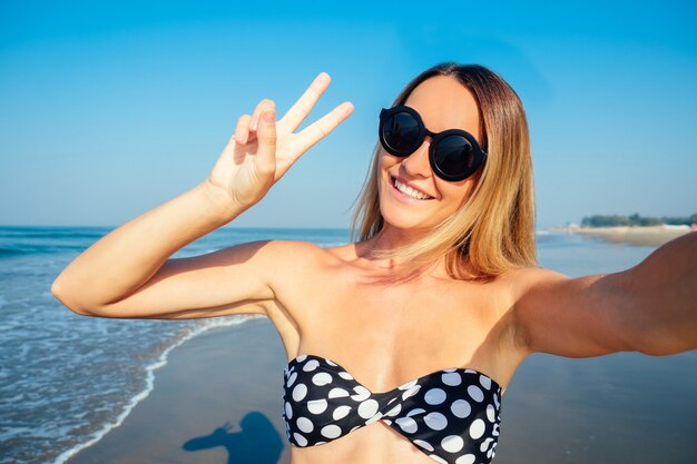 Lächelnde und schöne Frau, die Selfie im Urlaub tut.