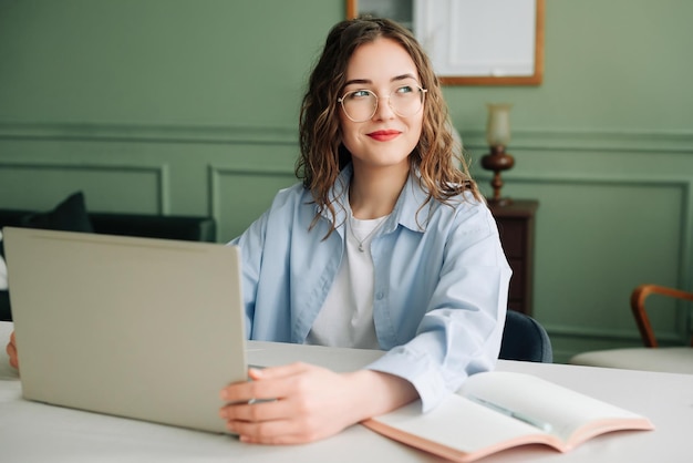 Lächelnde Unternehmensmitarbeiterin, die am Laptop im modernen Büro arbeitet, Marketingmanagerin oder