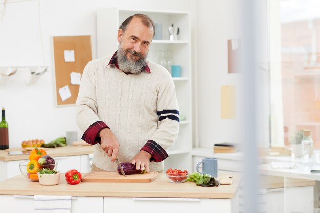 Lächelnder älterer Mann, der in der Küche kocht